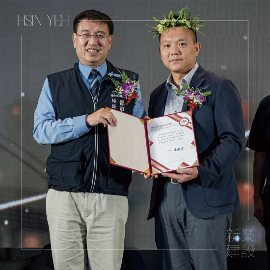 「2025臺(tái)中建築獎(jiǎng)?lì)C獎(jiǎng)典禮」，以金馬獎(jiǎng)模式現(xiàn)場(chǎng)揭曉各獎(jiǎng)項(xiàng)得主，由頒獎(jiǎng)人臺(tái)中市都市發(fā)展局 李正偉局長(zhǎng)(左一)，恭賀新業(yè)建設(shè) 吳志輝建築師(右一) 榮獲殊榮。