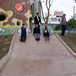 新業(yè)建設(shè)卓勝隆董事長(中)與來賓童心大發(fā)，一起玩溜滑梯。