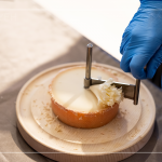 半硬質(zhì)家族的修道士(TETE DE MOINE)，呈小型鼓狀，外殼有點油膩、呈褐色，乳酪團結(jié)實且濃郁，隨著熟成顏色會加深，以轉(zhuǎn)臺式乳酪削切器，削成花摺邊小花苞。