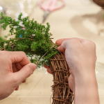 先以鐵絲穿過(guò)藤圈並收好，抓一把雪松，繞過(guò)後拉緊，再取一把雪松，在第一把根部接上，以此將雪松綁完。