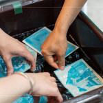 將明信片輕放入水箱中，清洗掉藥水後，隨著雙氧水的洗禮，藍(lán)曬圖像逐漸浮現(xiàn)。