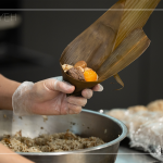 將粽葉三分之一處折起，交叉形成漏斗狀，轉(zhuǎn)著處末端折一個(gè)折角，再將內(nèi)餡包入。