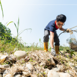 從石縫中抽出韌性的橡膠圈，岸邊的垃圾也不可輕忽，可能會(huì)因?yàn)闈q潮後的潮水而沖刷到溪裡。