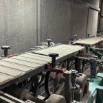 乾燥處理過的磁磚，整齊地陳列在輸送臺上，準備進入下一道逐層施釉的工序。